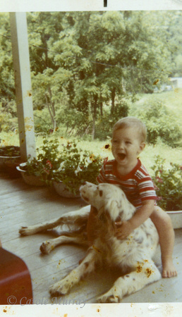 Kevin on Mamaw and Papaw Maddron's front porch, "riding" one of their dogs!